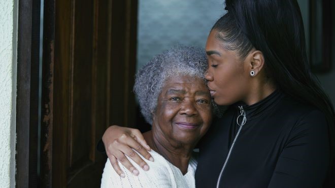 older black woman hugging a younger black woman