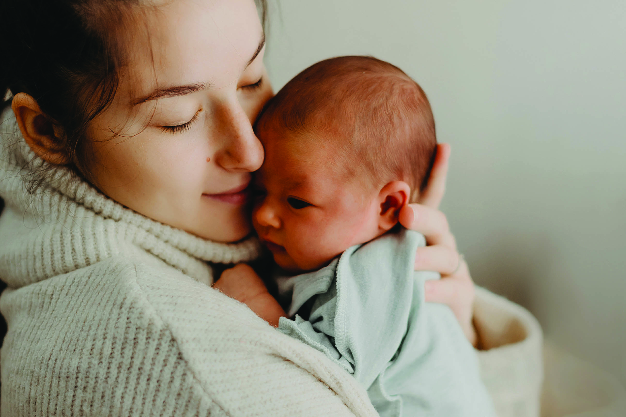 A woman holds a newborn baby close to her