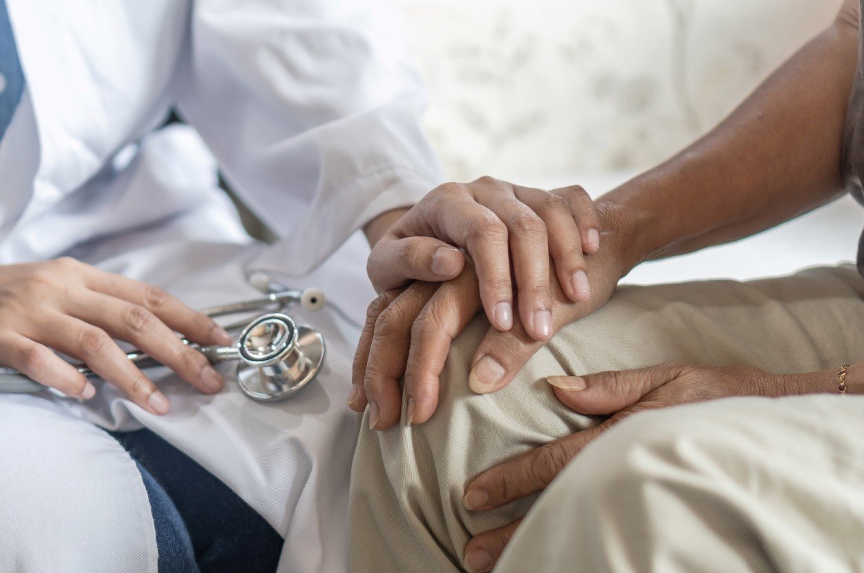 A doctor places a comforting hand on top of patient's hand