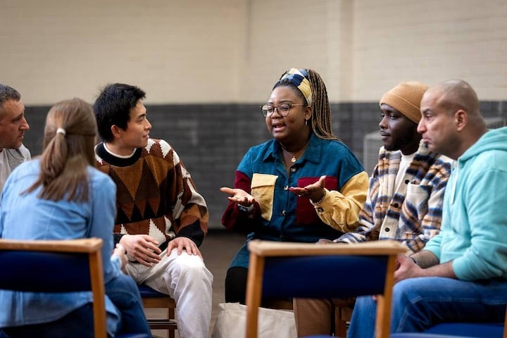 Diverse group of adults sitting in a circle and engaging in friendly conversation.