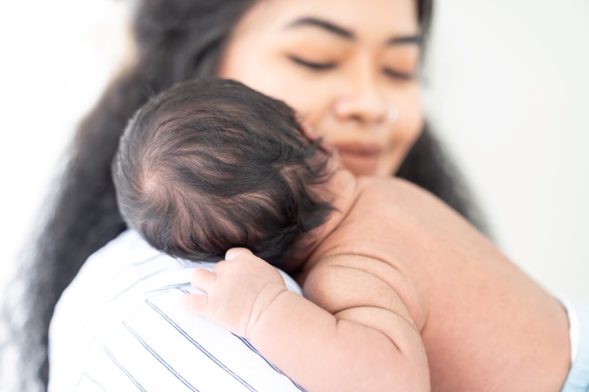 mother holding an infant on her shoulder