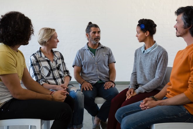 a group of people talking in group therapy