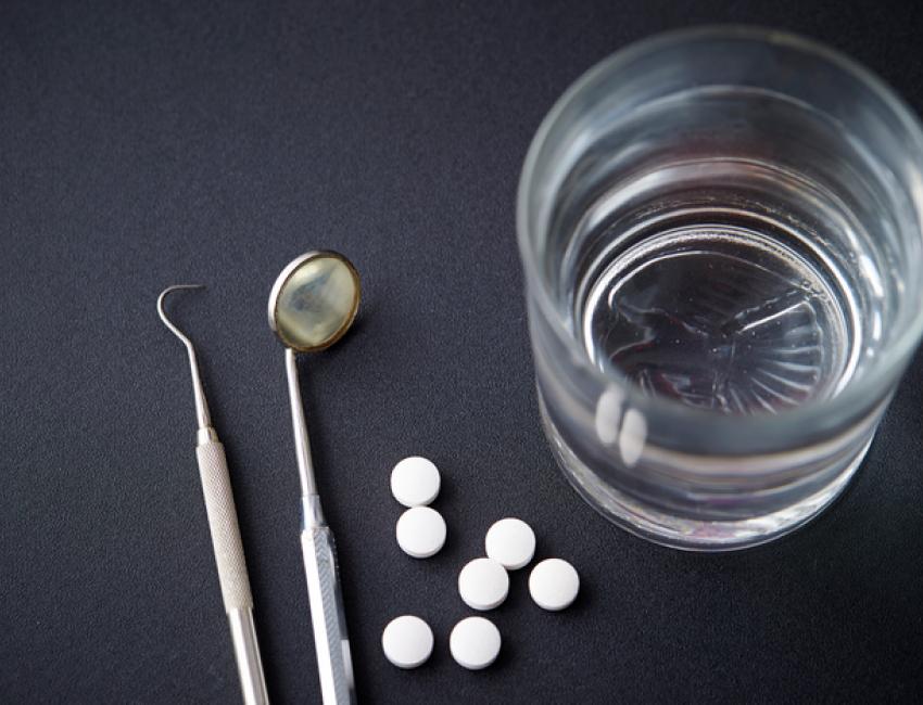 dental tools, pills, and a glass of water