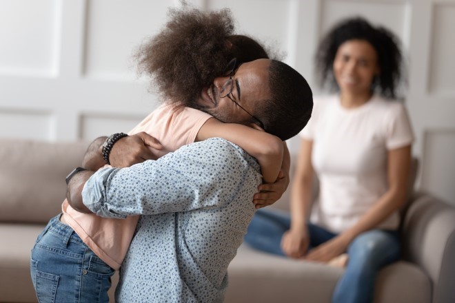 Man hugging daughter while mom looks on