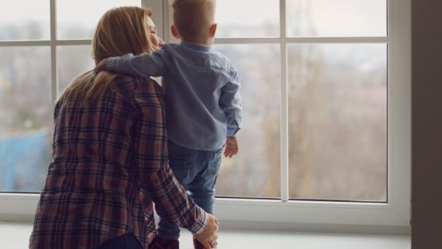 a mom and baby looks out a window