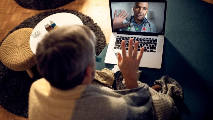 Person waving hello to their health care provider via a telemedicine visit