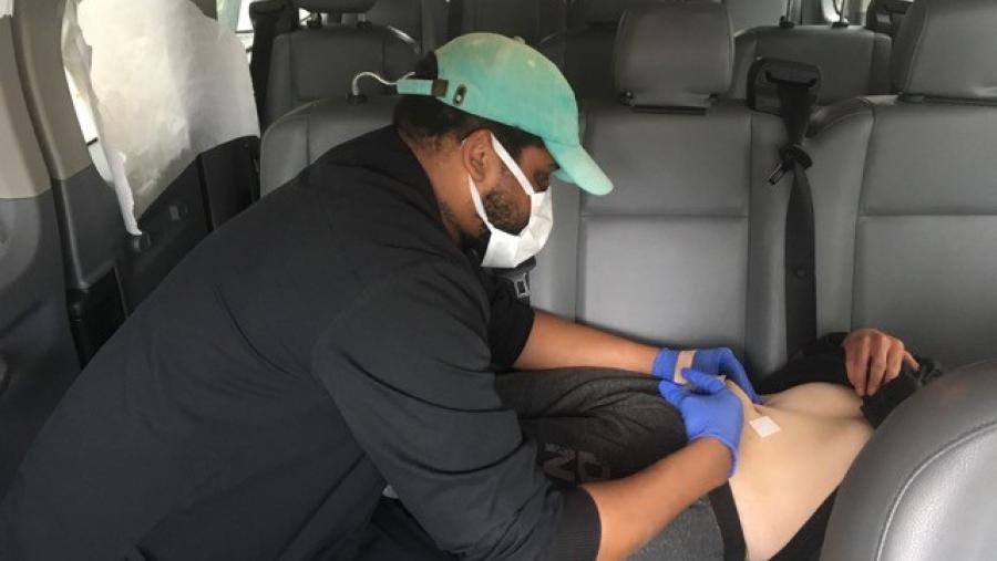 Image of Stanley Moody, L.P.N., administering a medication injection in a van. 
