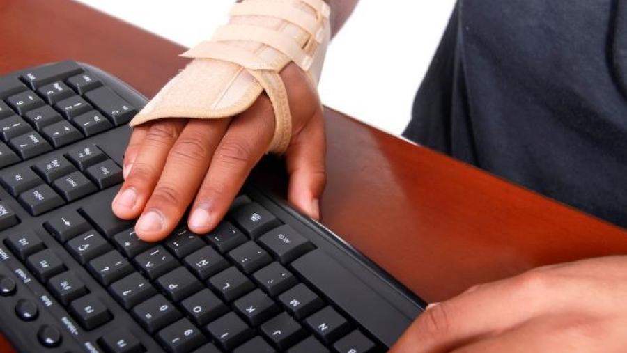 bandaged hand typing on keyboard showing carpal tunnel