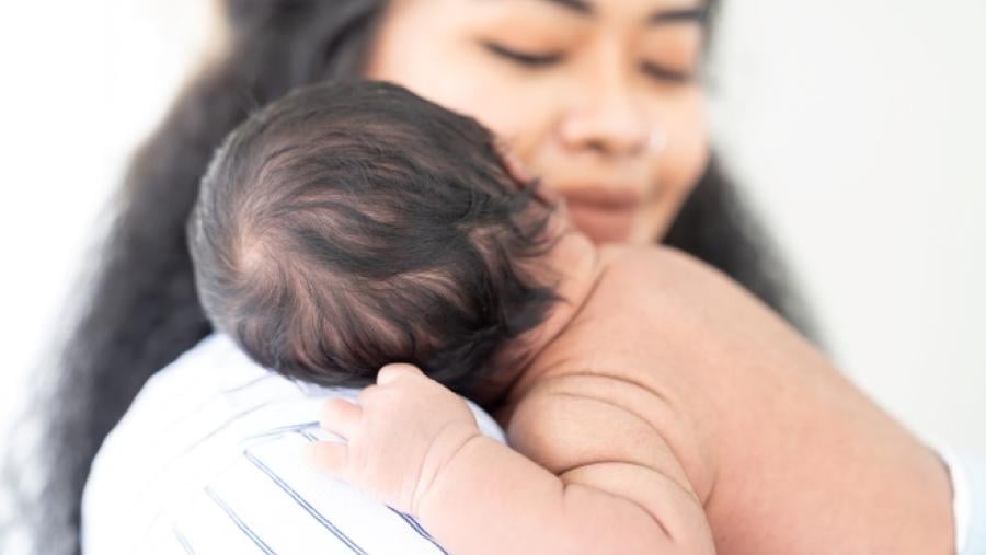 mother holding an infant on her shoulder