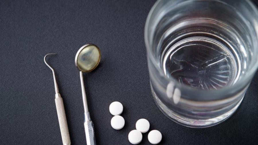 dental tools, pills, and a glass of water