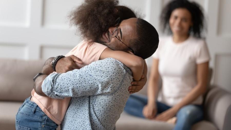 Man hugging daughter while mom looks on