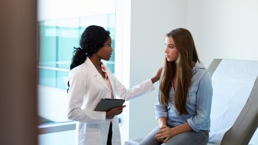 A healthcare provider talks with a young adult patient